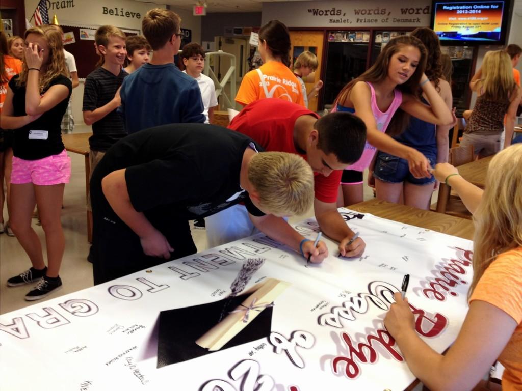 Class of 2017 students sign the Commitment to Graduate banner in the school library during Freshman Orientation on August 21, 2013.
