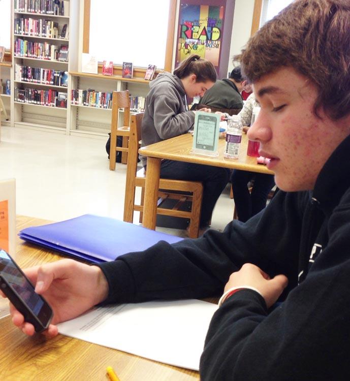 Senior Max Ayers spends time with his cell phone during his free period in the library on Wednesday, April 30.