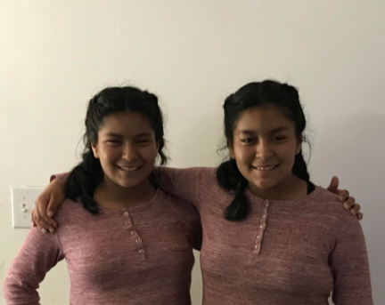 Identical twins Jazzmyn and Deborah Prado pose together in matching shirts.